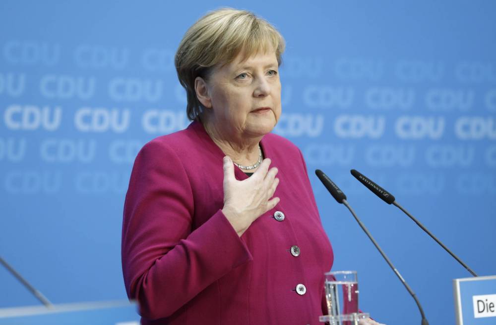 Меркель сидя слушала гимн во избежание очередного приступа дрожи