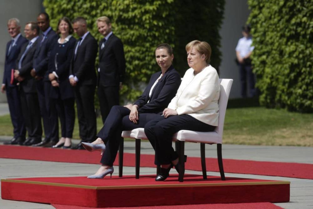 Ангела Меркель пытается преодолеть дрожь и сидит во время гимна