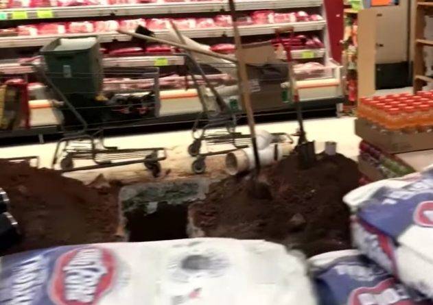 На шокирующем видео рабочие делают дыру в полу продуктового магазина, а сотрудники смахивают строительный мусор с продуктов