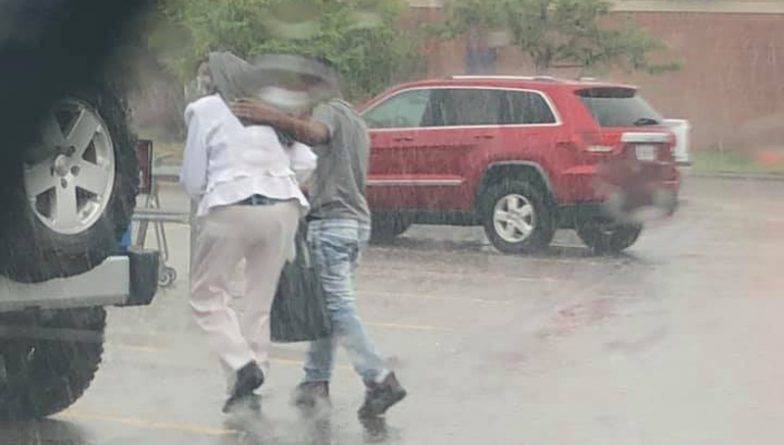 Парень прикрыл пожилую женщину своей курткой, чтобы она не промокла под дождем