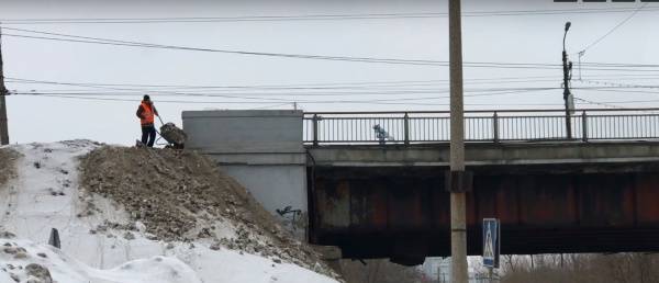 В Челябинске рабочие сбрасывают грязный снег в реку Миасс
