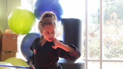 Юная тхэквондистка тренирует детей боевым искусствам.