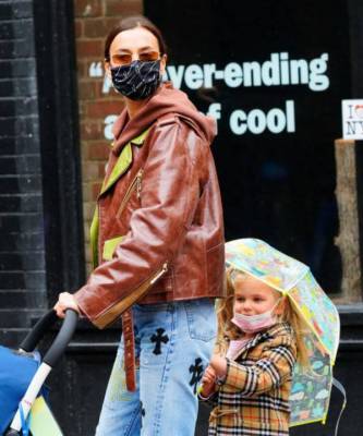 Кожаная куртка карамельного цвета + джинсы с принтом: Ирина Шейк на прогулке с дочерью