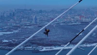 Альпинист очищает от наледи мост на остров Русский — видео с беспилотника