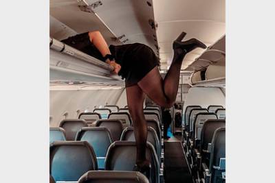 Фото повисшей на багажной полке стюардессы в мини-платье впечатлило подписчиков