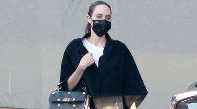 Пончо, сапоги и сумка Valentino: нескучный total black от Анджелины Джоли