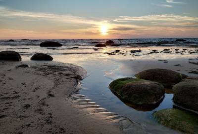 Гладь воды и валуны: фотограф показал закат на пляже в Липово