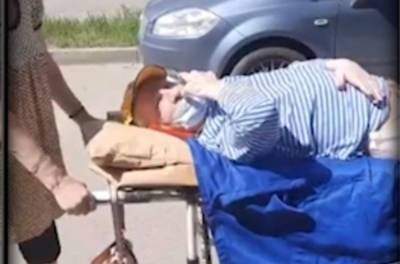 Женщина везла мужа домой из больницы по улице на каталке