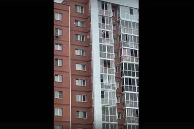 В Иркутске мужчина с ребенком забрался на ограждение балкона высотки