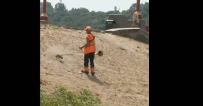 В Киеве на Трухановом острове коммунальщик мотокосой вспахивал песок (видео)