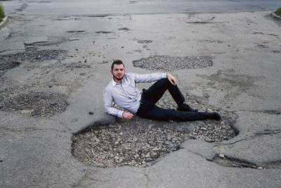 Рязанец сфотографировался в огромной дорожной яме в Канищеве