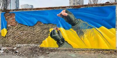 «Мы выстоим, мы победим». В Киеве на Оболони появился мурал с украинским военным, зашивающим флаг Украины