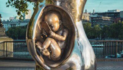 Скульптура младенца в утробе матери с мобильным телефоном