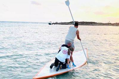 Парамедики МАДА плыли на доске для серфинга, чтобы оказать помощь пострадавшему в воде мужчине
